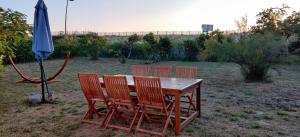 a wooden table with four chairs and an umbrella at Maison au bord de dune et océan in Labenne +2 photos