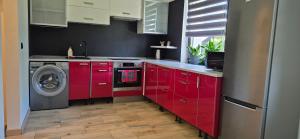 a kitchen with red cabinets and a washing machine at Quiet Apartment in Oświęcim