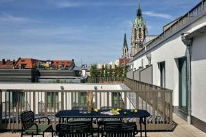 a balcony with a table and chairs and a view of a city at Schwan Locke in Munich