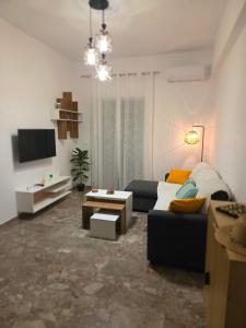 a living room with a couch and a tv at Loutraki Cozy Loft in Loutraki