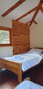 a bed in a room with a wooden wall at Tara Rafting Resort in Foča