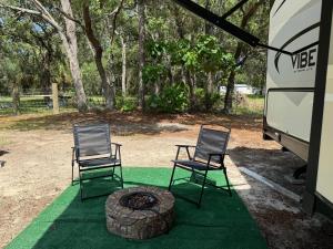 two chairs and a fire pit in front of a bus at Florida VIBE in Homosassa Springs