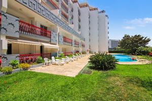 a large building with chairs and a swimming pool at T2 Tivoli in Vilamoura