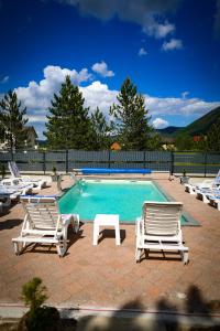 a swimming pool with two lawn chairs and a table at Natural Dream Blidinje in Rudo Polje