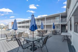 a deck with tables and chairs and blue umbrellas at Surfside - Boutique Studio Condo with Pool in Hampton
