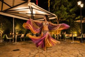 a woman in a colorful dress dancing at a party at Lido Corfu Sun Hotel 4 Stars All-inclusive in Benitses +51 photos