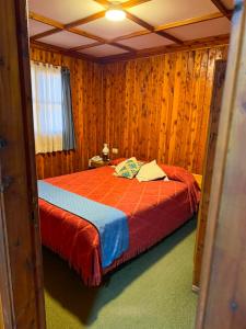 a bedroom with a bed in a room with wooden walls at Complejo Villa Azul in Esquel