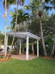 a white pergola in a park with palm trees at Regiane Residence in Wellington
