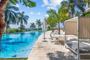 a swimming pool with tables and chairs and palm trees at Beachfront Modern Sanctuary - Bolongo in Higuera Blanca