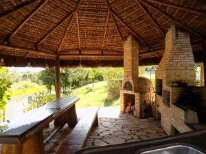 an outdoor patio with a pizza oven under a straw roof at Pousada Rural Paraíso in Águas de São Pedro