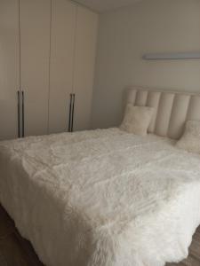 a white bed with white sheets and pillows at Рока Ресиденс 1 in Ravda