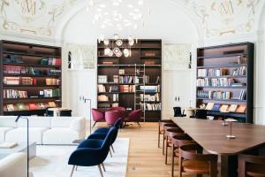 Eine Bibliothek mit Tisch, Stühlen und Bücherregalen in der Unterkunft MACAM Hotel in Lissabon