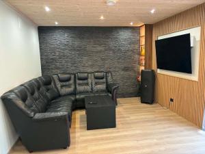 a living room with a leather couch and a flat screen tv at Riverside Sauna House in Savala