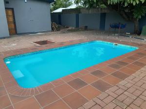 a swimming pool with a tile floor and a blue at Villa Central in Francistown