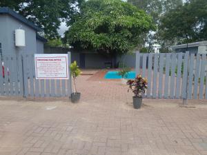 a fence with a sign and plants in front of it at Villa Central in Francistown