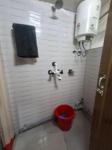 a bathroom with a red bucket in a white wall at GD's Homestay in Shillong