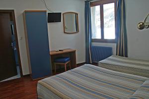 a hotel room with two beds and a desk at Hotel La Belle Aude in Matemale