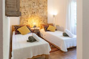 a room with two beds with white sheets and yellow pillows at Villa Can Gavarres in Bell-Lloch