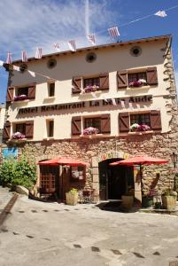 a building with red umbrellas in front of it at Hotel La Belle Aude in Matemale