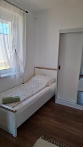 a white bedroom with a bed with a window at Mirtusz Apartmanház in Balatongyörök