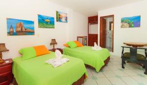 two beds in a room with green sheets at The Island Home in Puerto Ayora