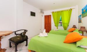 a bedroom with two green beds and a table at The Island Home in Puerto Ayora