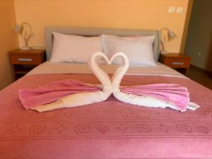 two towel swans making a heart on a bed at Sunset Residence Blizikuce in Budva