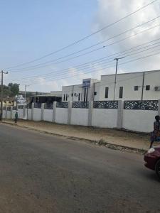 a person riding a car on a street next to a fence at The Royam Hotel and Apartments in Ibadan