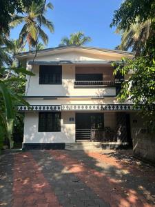 a white house with a brick driveway in front of it at Bluebell Homes Near Beypore Beach Kozhikode in Kozhikode