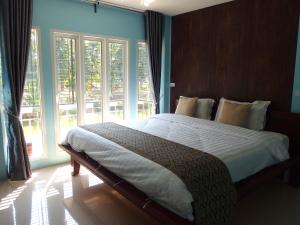 a bedroom with a large bed with a large window at Muaan Resort in Suphan Buri