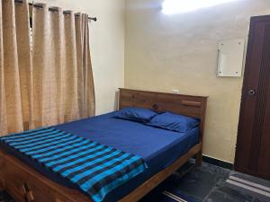 a bedroom with a bed with a blue comforter at Bluebell Homes Near Beypore Beach Kozhikode in Kozhikode