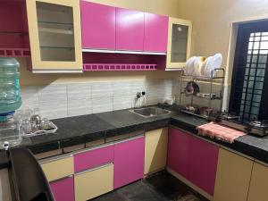 a kitchen with pink and purple cabinets and a sink at Bluebell Homes Near Beypore Beach Kozhikode in Kozhikode