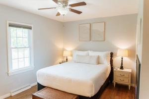 a bedroom with a white bed and a ceiling fan at Family Friendly Getaway with Fire Pit & Swing Set in Geneva