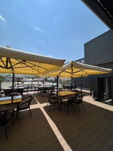 a deck with tables and chairs with yellow umbrellas at Hotel Alto in Karakol