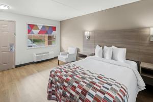 a hotel room with a bed and a chair at Red Roof Inn & Suites Marysville in Marysville