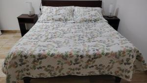 a bed with a comforter with two nightstands and two tables at Hotel santa Rosa spa in Ovalle