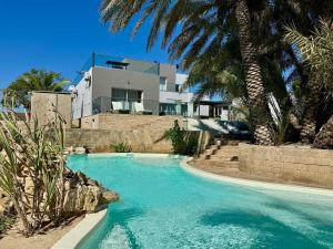 a swimming pool in front of a house with palm trees at Villa Céllia in Tsivonoakely