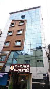 a tall glass building with a sign in front of it at V-Suites in Bangalore