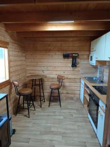 a kitchen with two tables and stools in a cabin at Ferienhaus Mit Blick auf die Müritz in Rechlin +8 photos