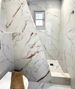 a bathroom with marble walls and a toilet and a window at V Angelo Prestige Rooms- Adults Only in Perissa +26 photos