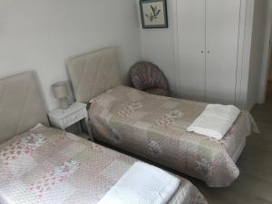 two twin beds in a room with a table at HabiKuchta Foz in Figueira da Foz