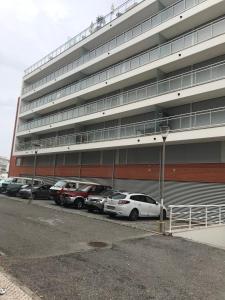 a parking lot with cars parked in front of a building at HabiKuchta Foz in Figueira da Foz