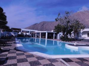 a swimming pool in a resort with mountains in the background at V Angelo Prestige Rooms- Adults Only in Perissa