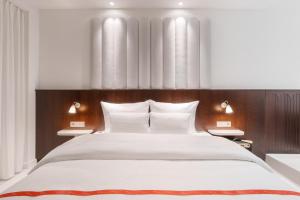 a bedroom with a large white bed with two lamps at Ruby Hanna Hotel Stuttgart by IHG in Stuttgart