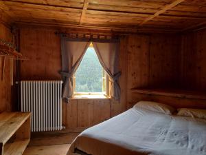 a bed in a wooden room with a window at Locanda Teggiate in Madesimo