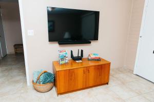 a flat screen tv on a wall with a wooden cabinet at NEW Desert Bloom Hideaway in Green Valley