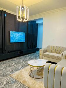 a living room with a couch and a tv at Kaizen Luxury Homes in Abuja