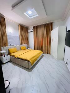 a bedroom with a bed with a yellow blanket at Kaizen Luxury Homes in Abuja