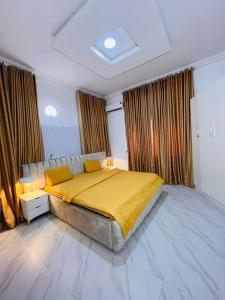 a bedroom with a large bed with yellow sheets at Kaizen Luxury Homes in Abuja