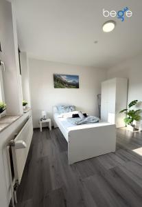 a white bedroom with a white bed and wooden floors at BEGE APARTMENTS WorkSpace in Marl